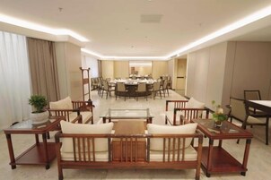 Un vestíbulo de hotel con una zona de estar, una mesa de comedor y una sala de conferencias.