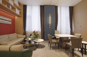 Una habitación de hotel moderna con sofá, mesa de comedor, sillas y una mesa de centro.