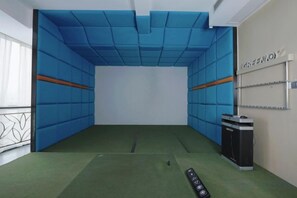 Una habitación con paredes acolchadas, alfombra verde y un cubo de basura.