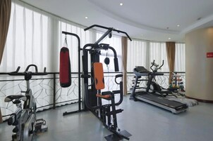 Un gimnasio con equipo de ejercicio, un saco de boxeo y una cinta de correr.