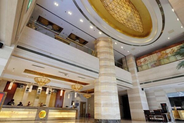 A hotel lobby with a reception desk, multiple floors, and a decorative ceiling.