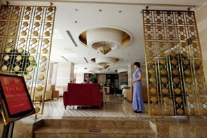 A hotel lobby with a red sofa, a tea bar sign, and a decorative gate with circular patterns.
