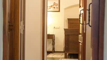 A hallway with a wooden cabinet, a rug, and a desk with a lamp.