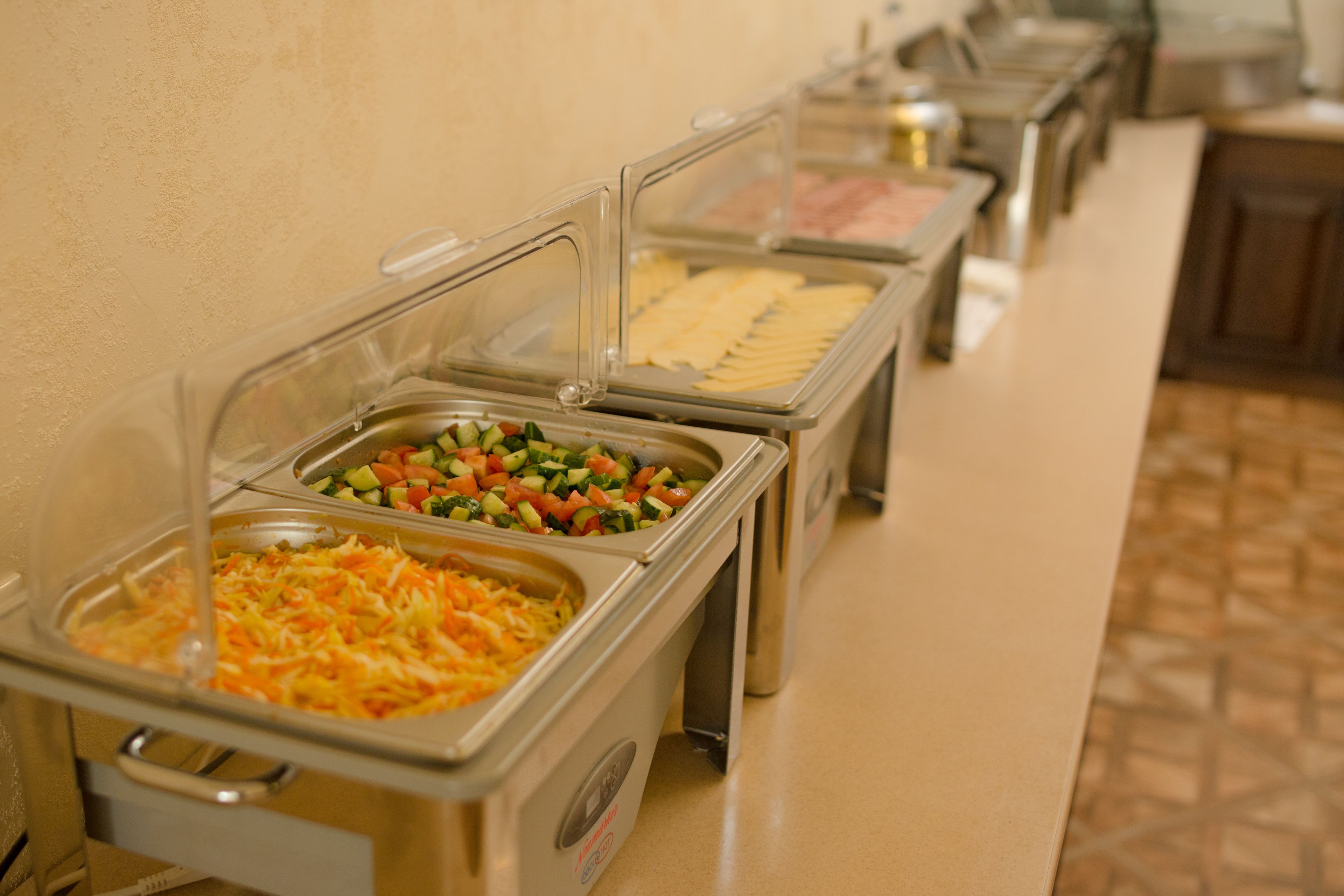 A buffet with various food options including salads, cheeses, and meats.