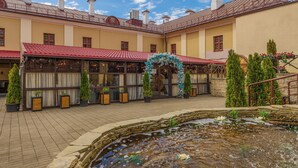 Un patio con una fuente, plantas en macetas y un edificio de techo rojo.