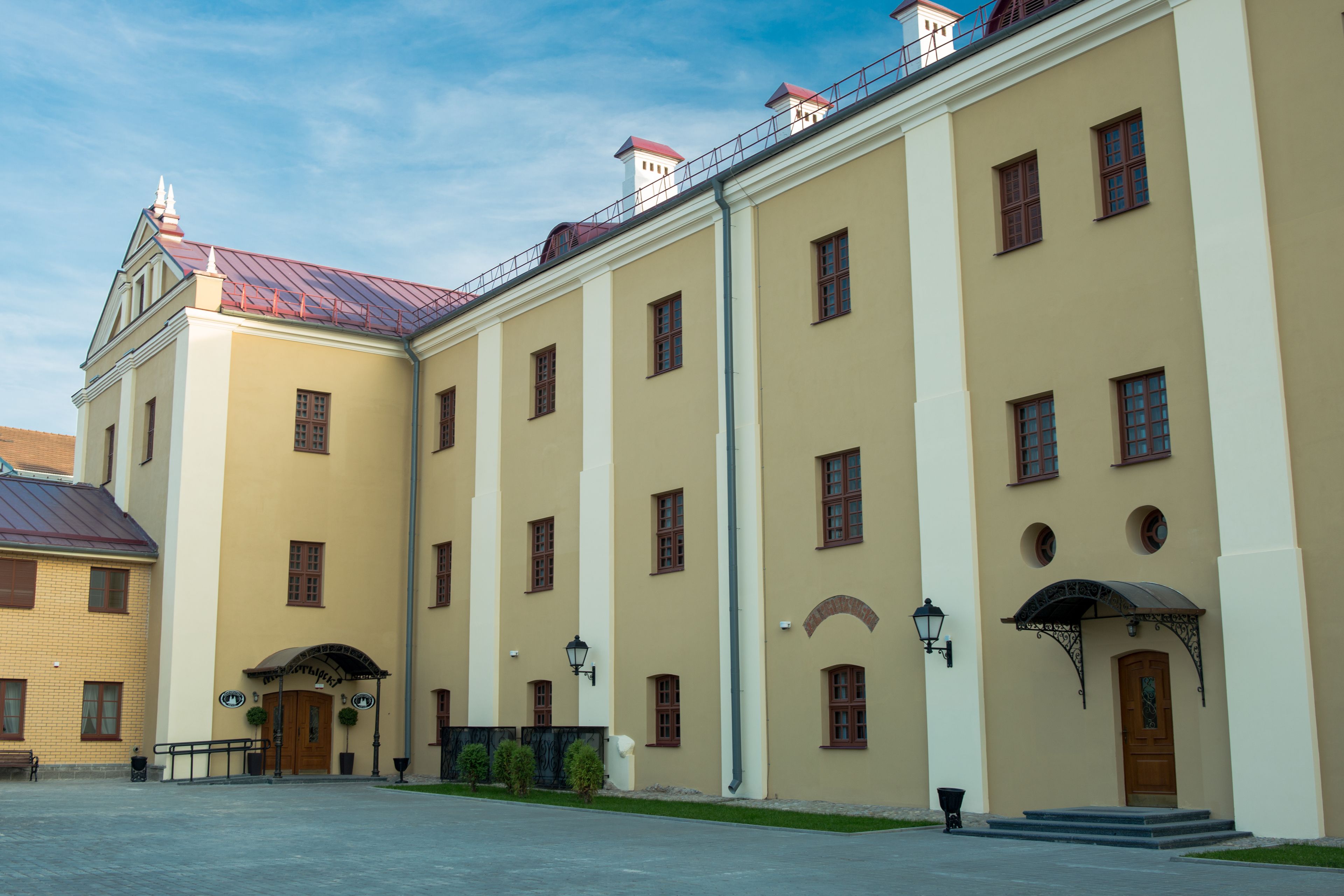 A large, beige building with multiple windows and a red roof.
