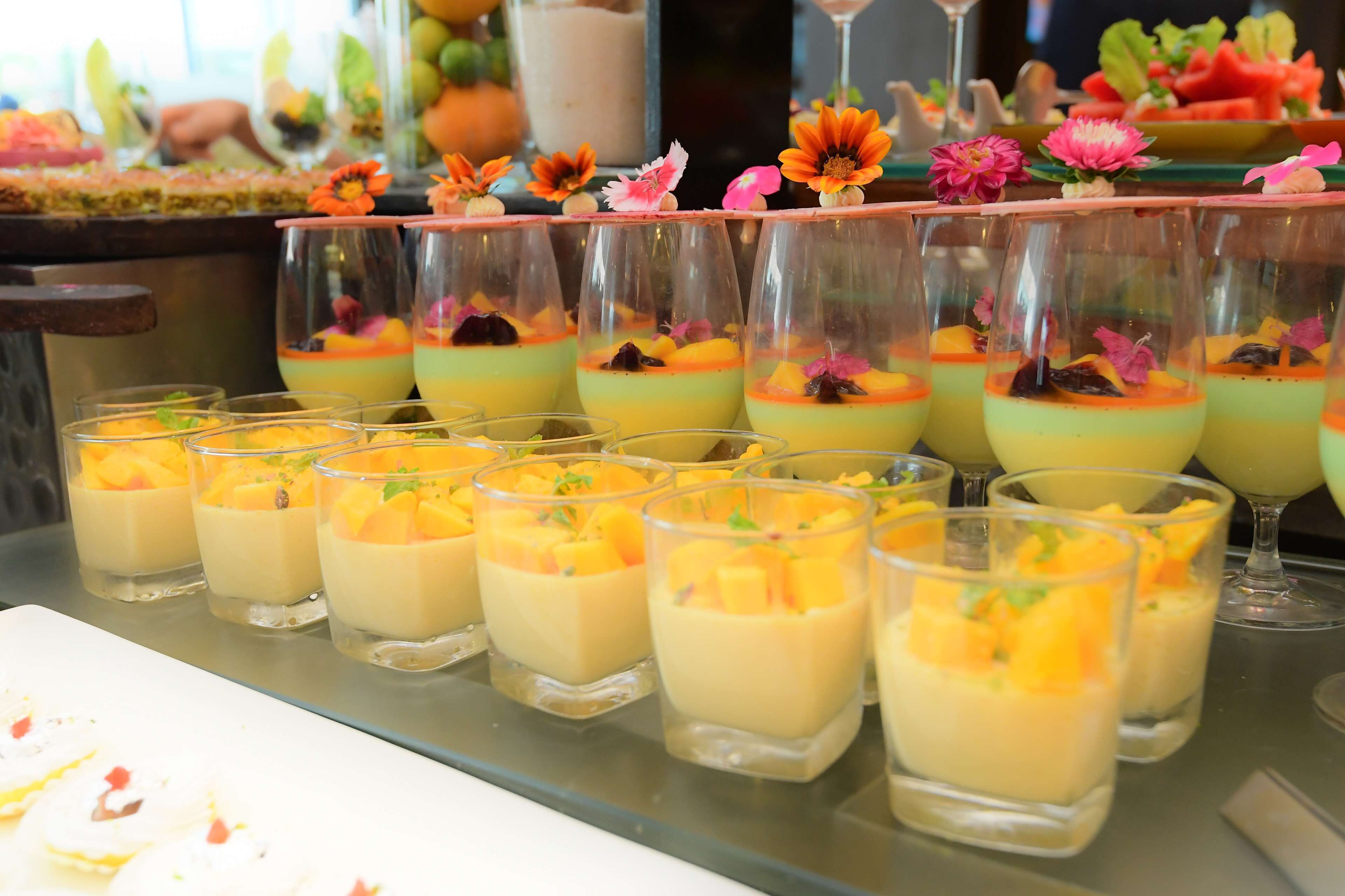 Un présentoir de desserts avec de nombreux verres contenant des desserts en couches et décorés de fruits.