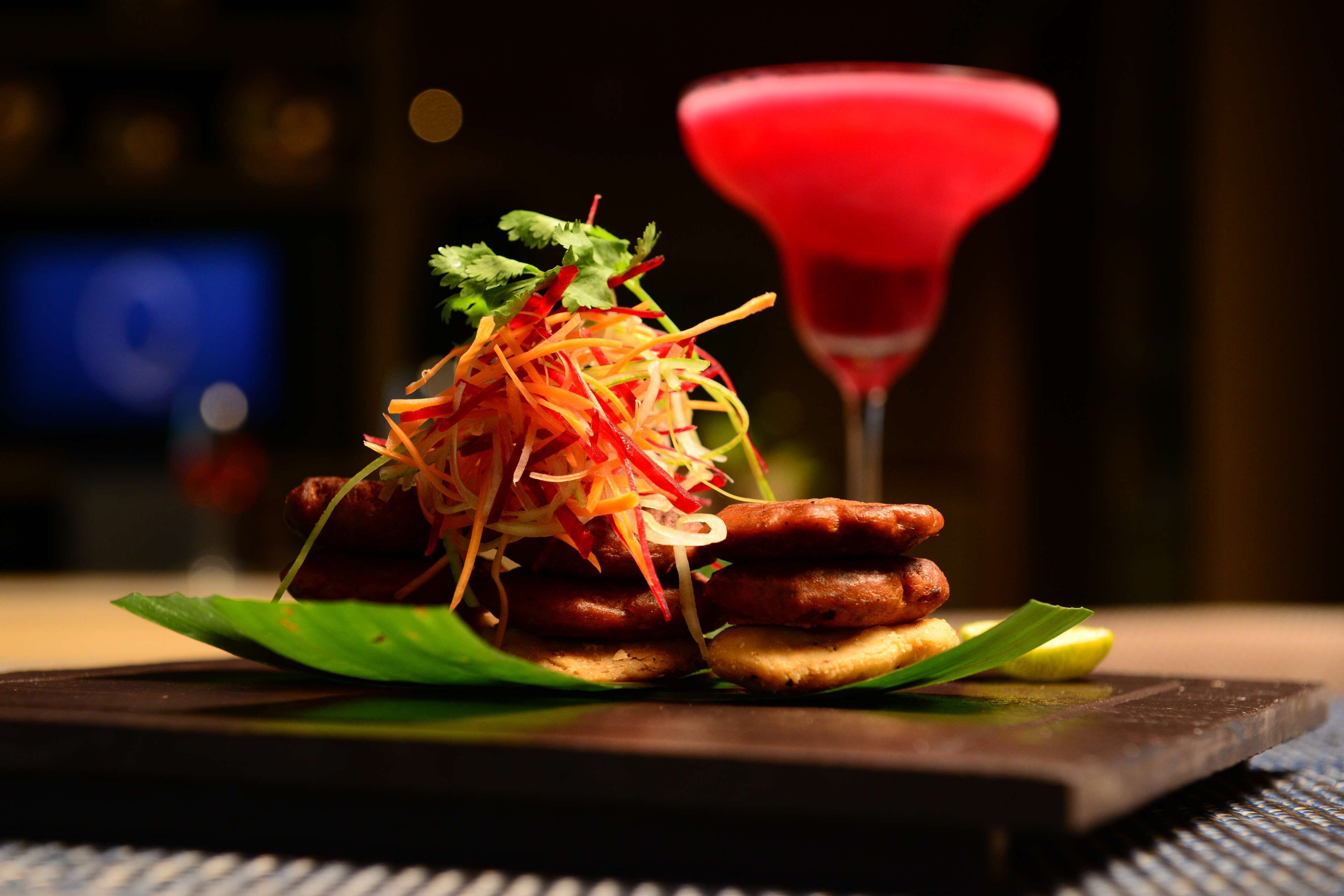 A dish with sausages, shredded vegetables, and a red drink on a wooden board.