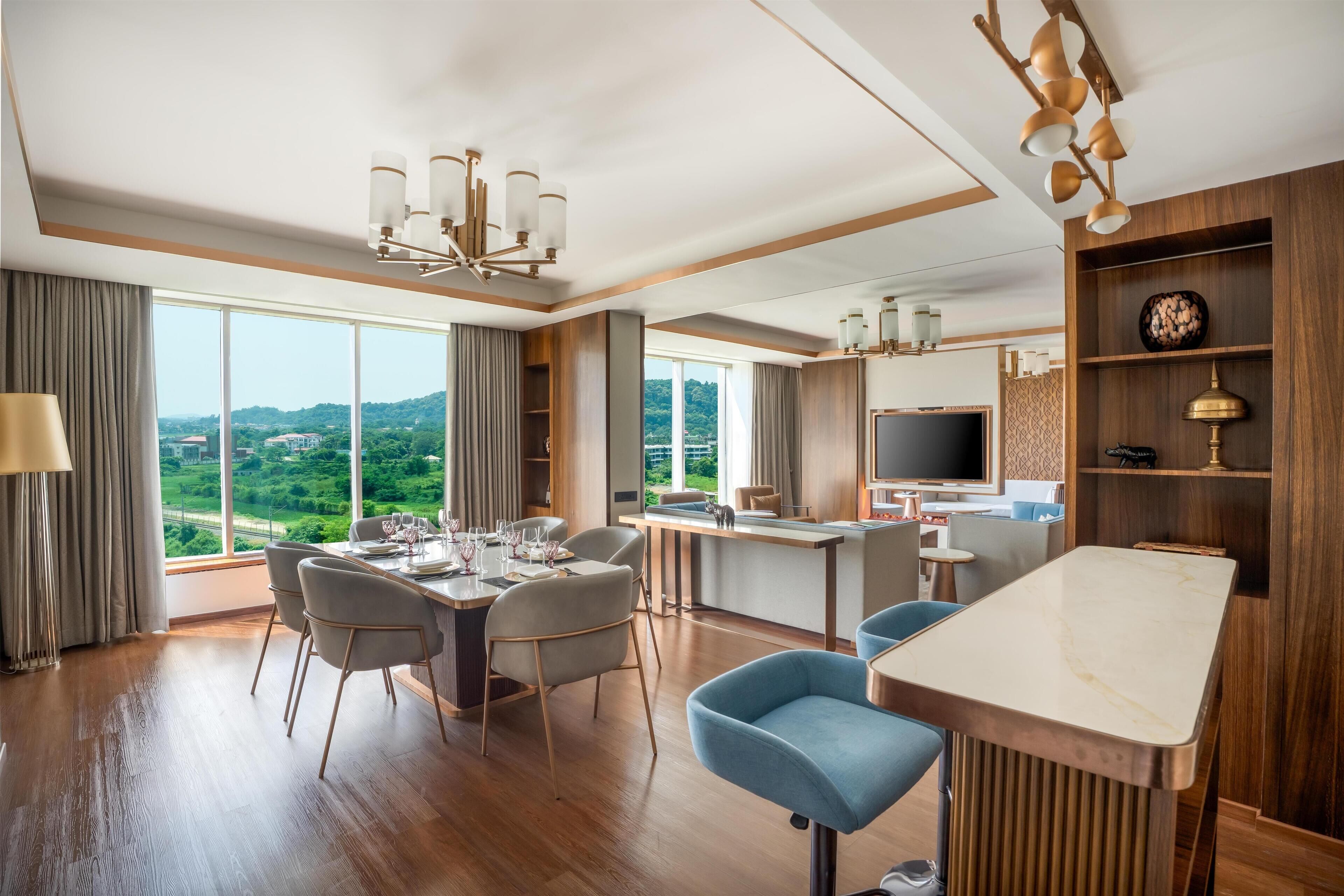 A modern hotel room with a dining area, a bar, and a TV.