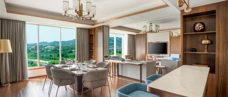 A modern hotel room with a dining area, a bar, and a TV.