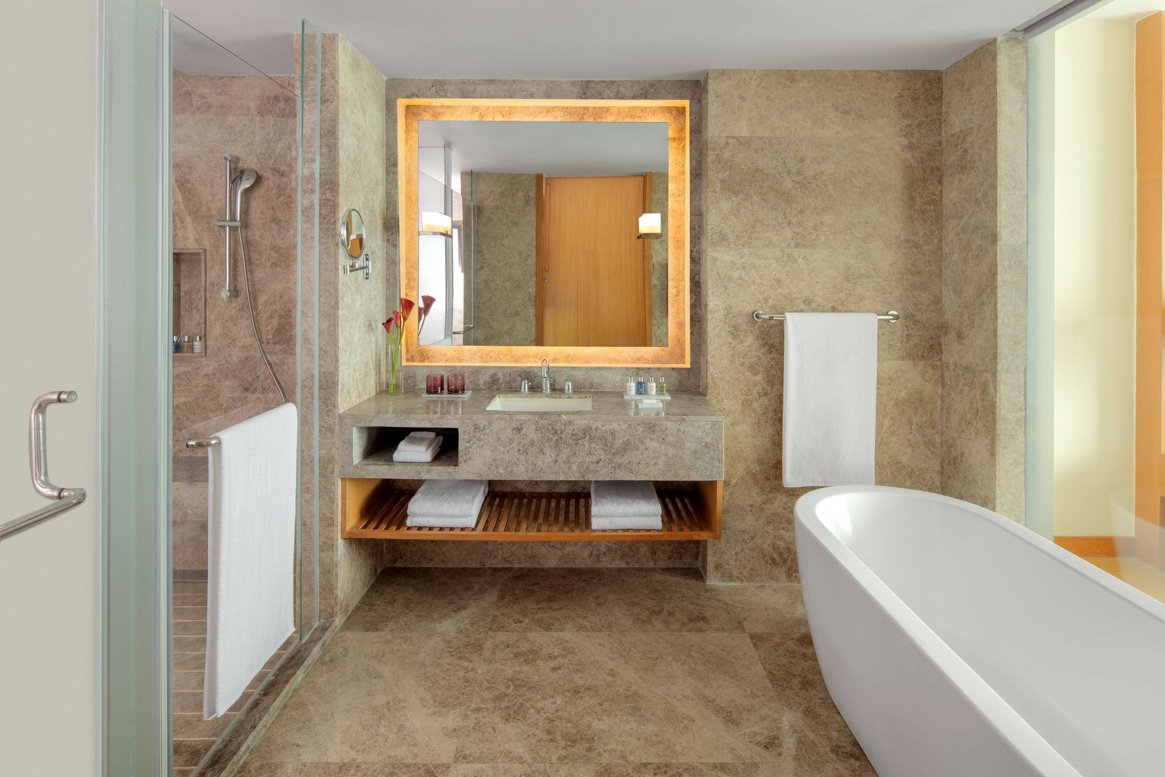 A modern bathroom with a glass-enclosed shower, a freestanding bathtub, and a vanity with a mirror.