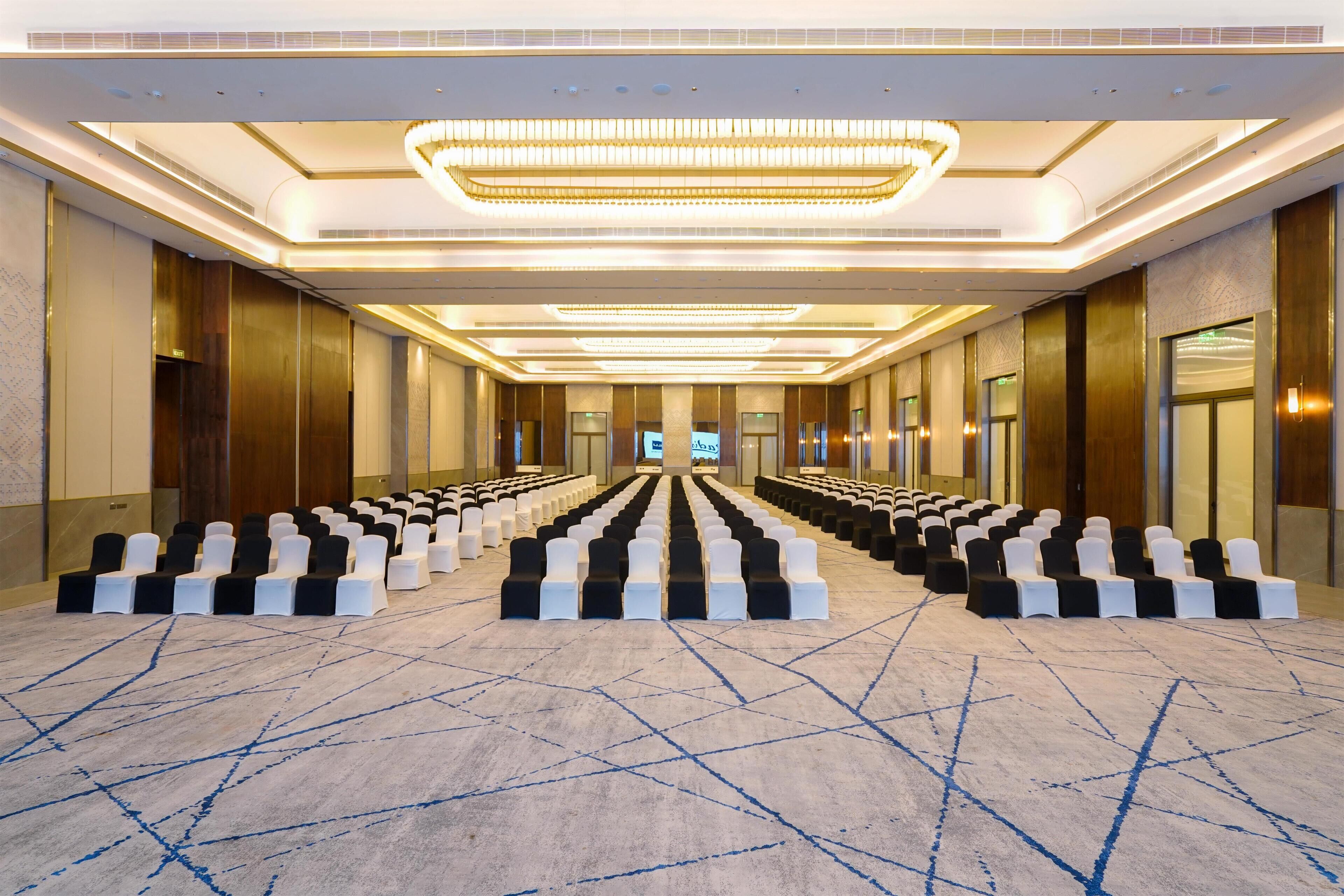 A spacious conference room with rows of chairs and a large chandelier.