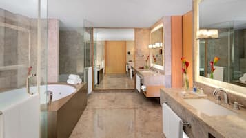 Un baño moderno con ducha envuelta en vidrio, una bañera grande y un lavamanos con espejo y lavabo.