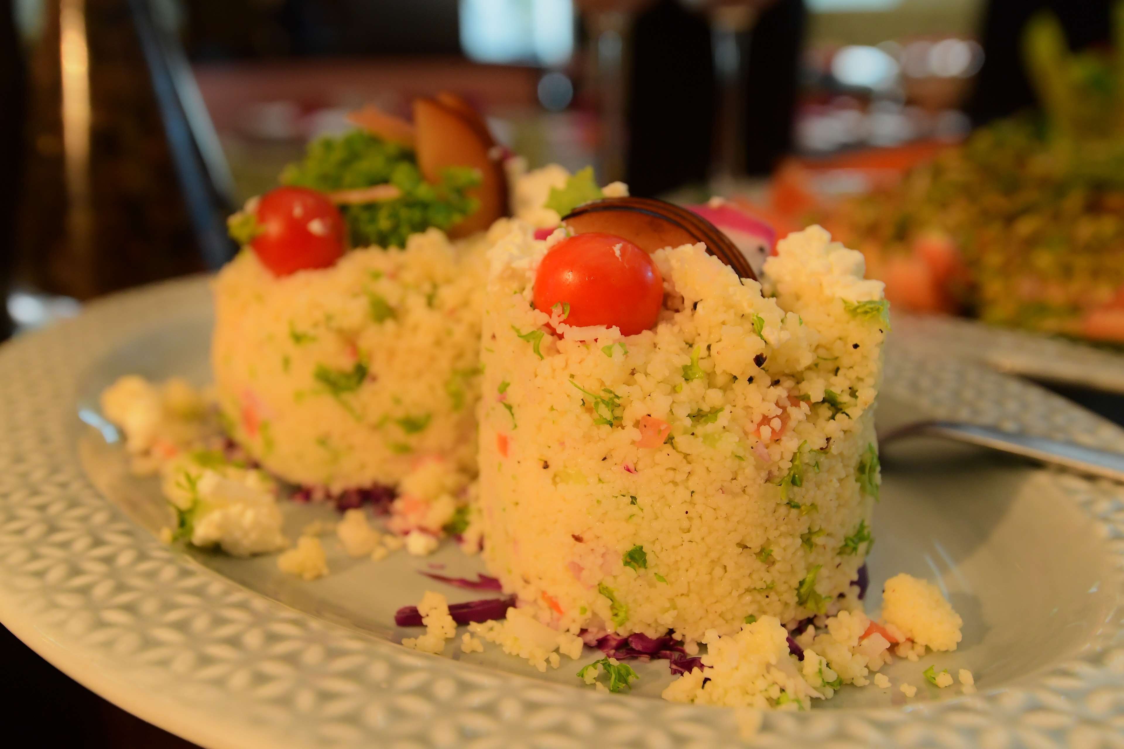 A plate with a food item, possibly a salad or rice dish, garnished with a cherry tomato.