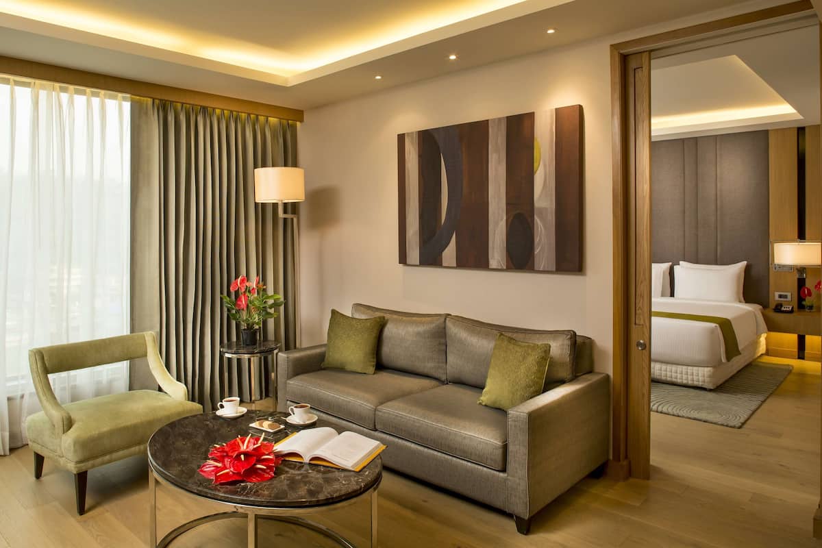 Ein Hotelzimmer mit Sofa, Sessel, Couchtisch und einem Bett.