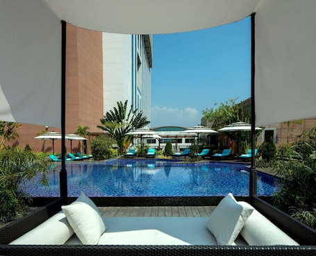 Una piscina al aire libre, sombrillas, sillones reclinables de piscina