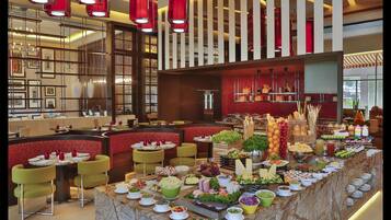 A buffet setup with various food items and a seating area with round tables and chairs.