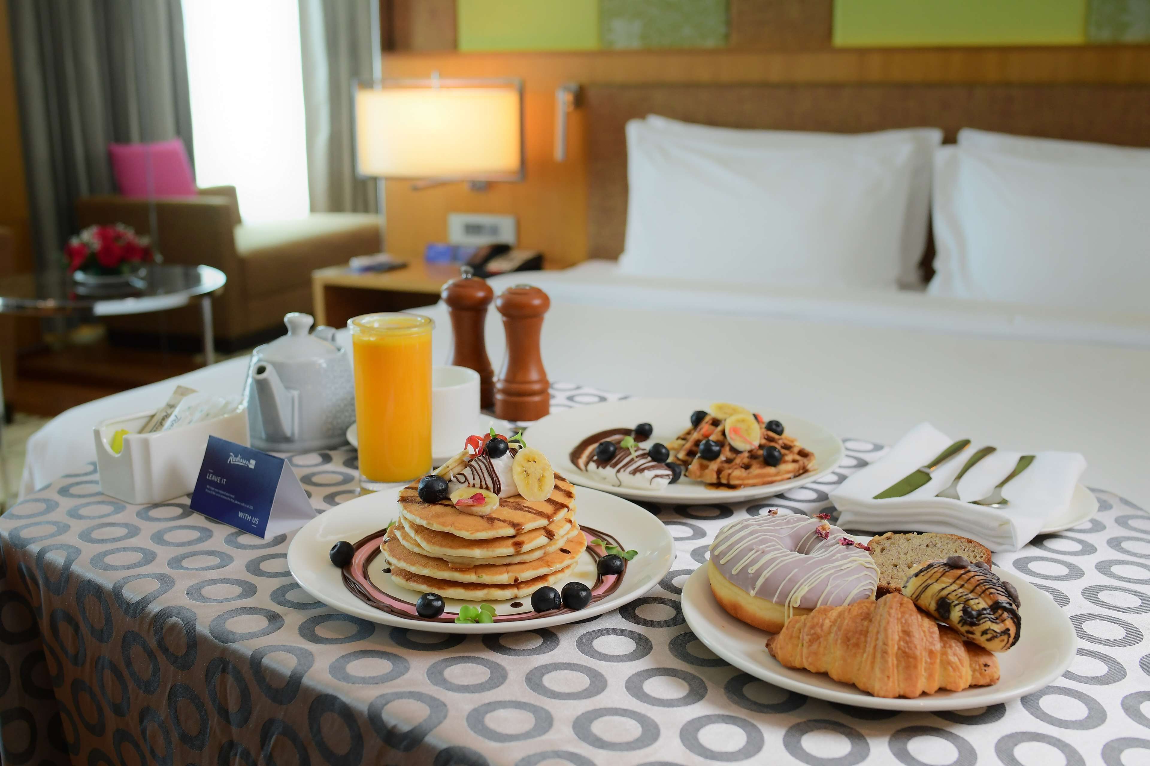 A breakfast table with pancakes, croissants, and a coffee pot.