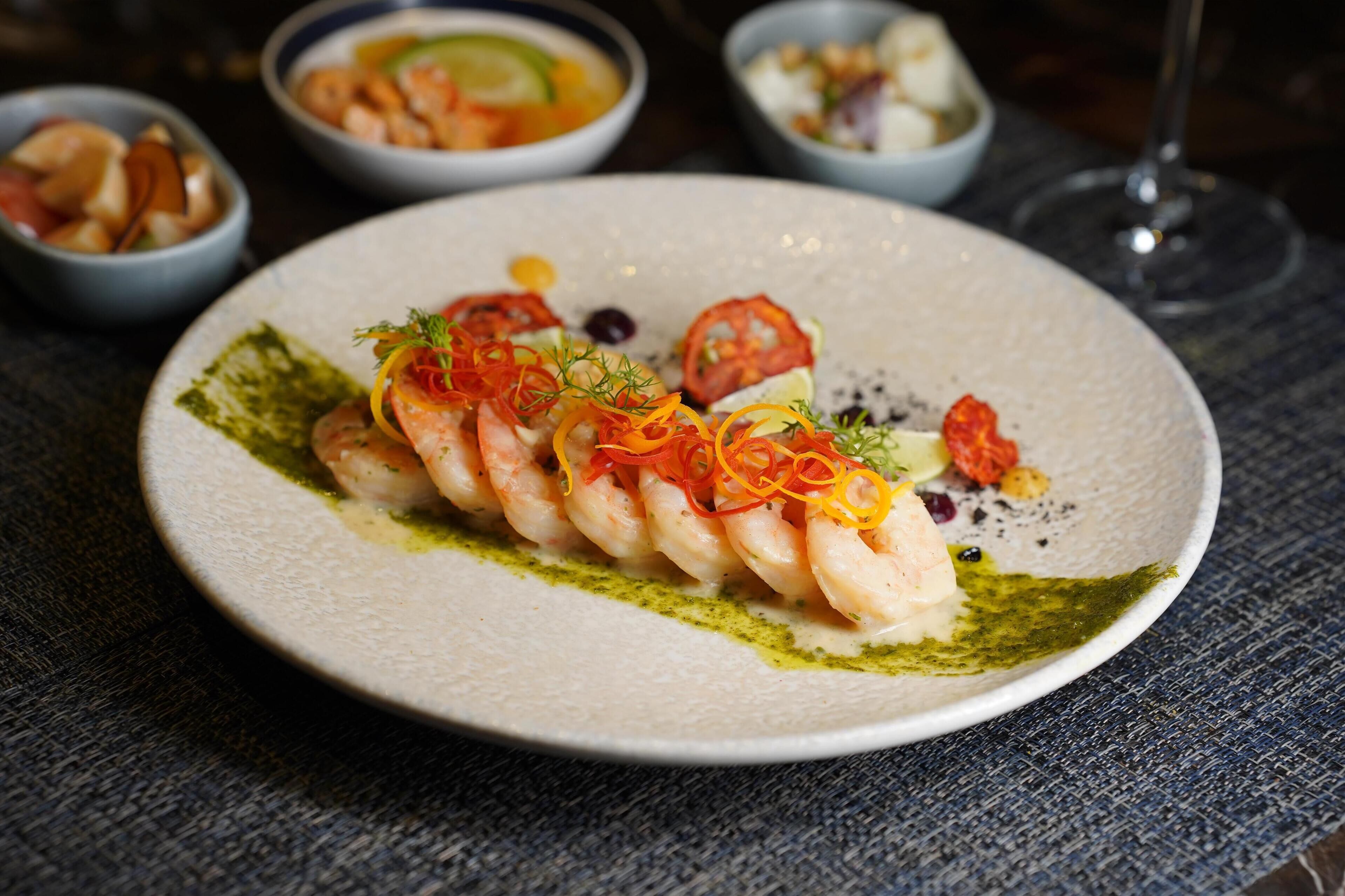 Une assiette de nourriture contenant des crevettes et des légumes, posée sur une nappe à motifs.
