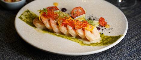 A plate of food with shrimp and vegetables on a textured tablecloth.