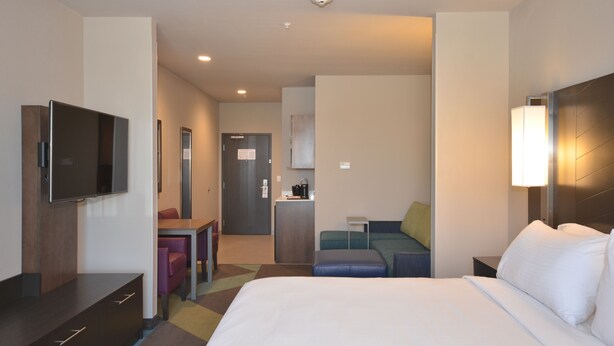 A hotel room with a bed, a desk, a television, a kitchenette, and a seating area. - Holiday Inn Express & Suites Oklahoma City Mid - Arpt Area by IHG (Oklahoma City)