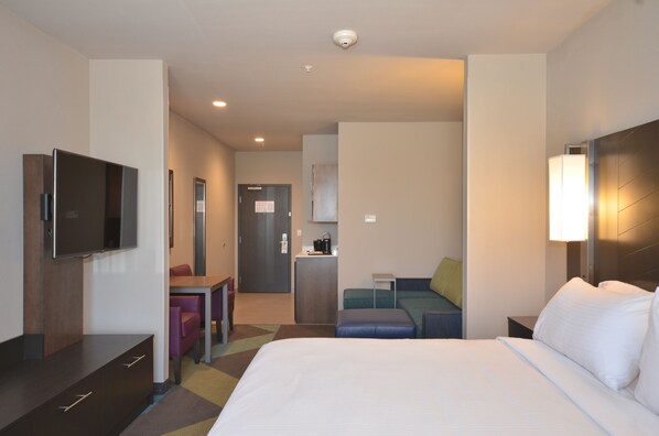A hotel room with a bed, a desk, a television, a kitchenette, and a seating area. - Holiday Inn Express & Suites Oklahoma City Mid - Arpt Area by IHG (Oklahoma City)