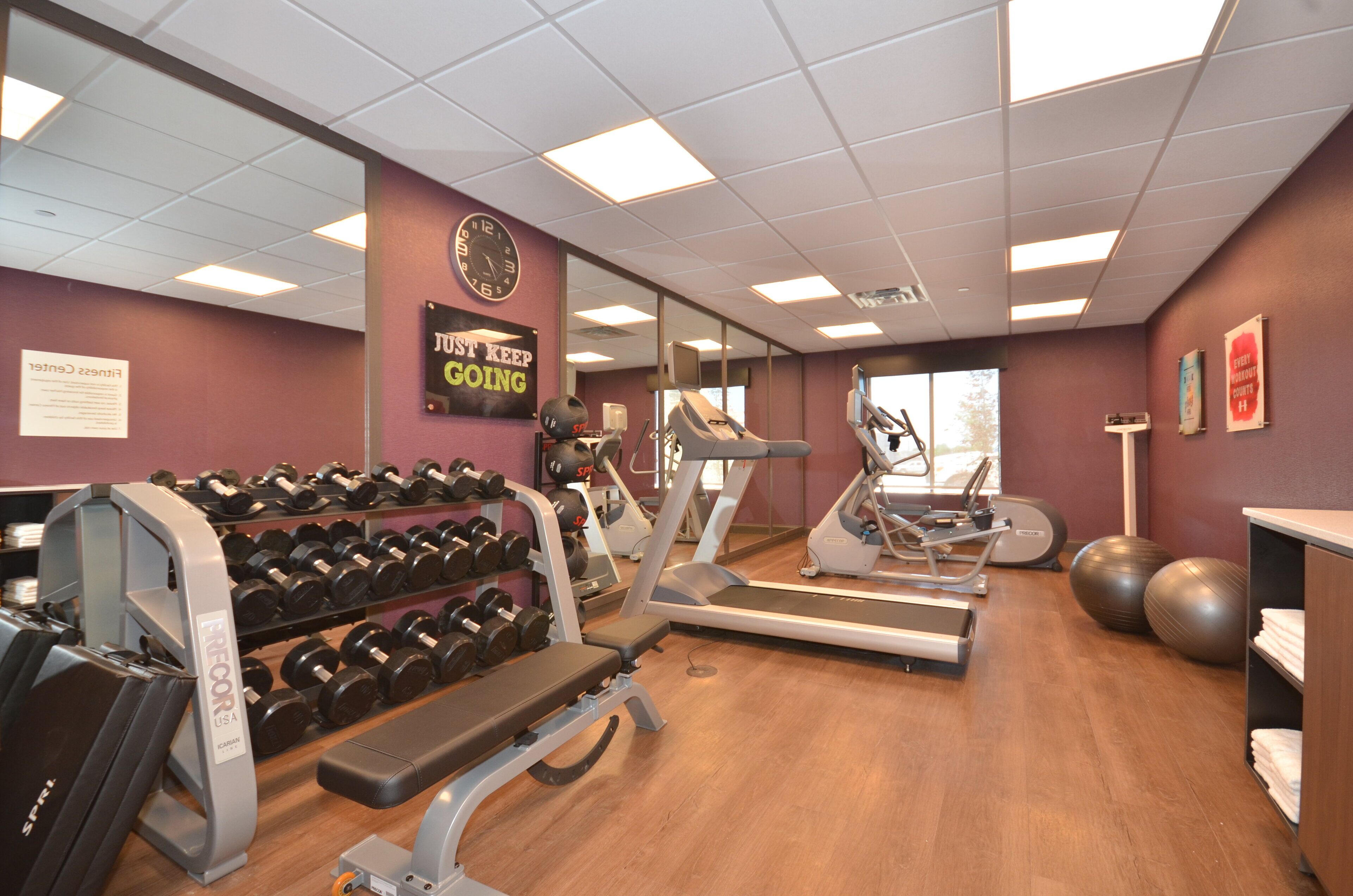 Une salle de sport équipée de tapis de course, d’haltères et de ballons d’exercice.
