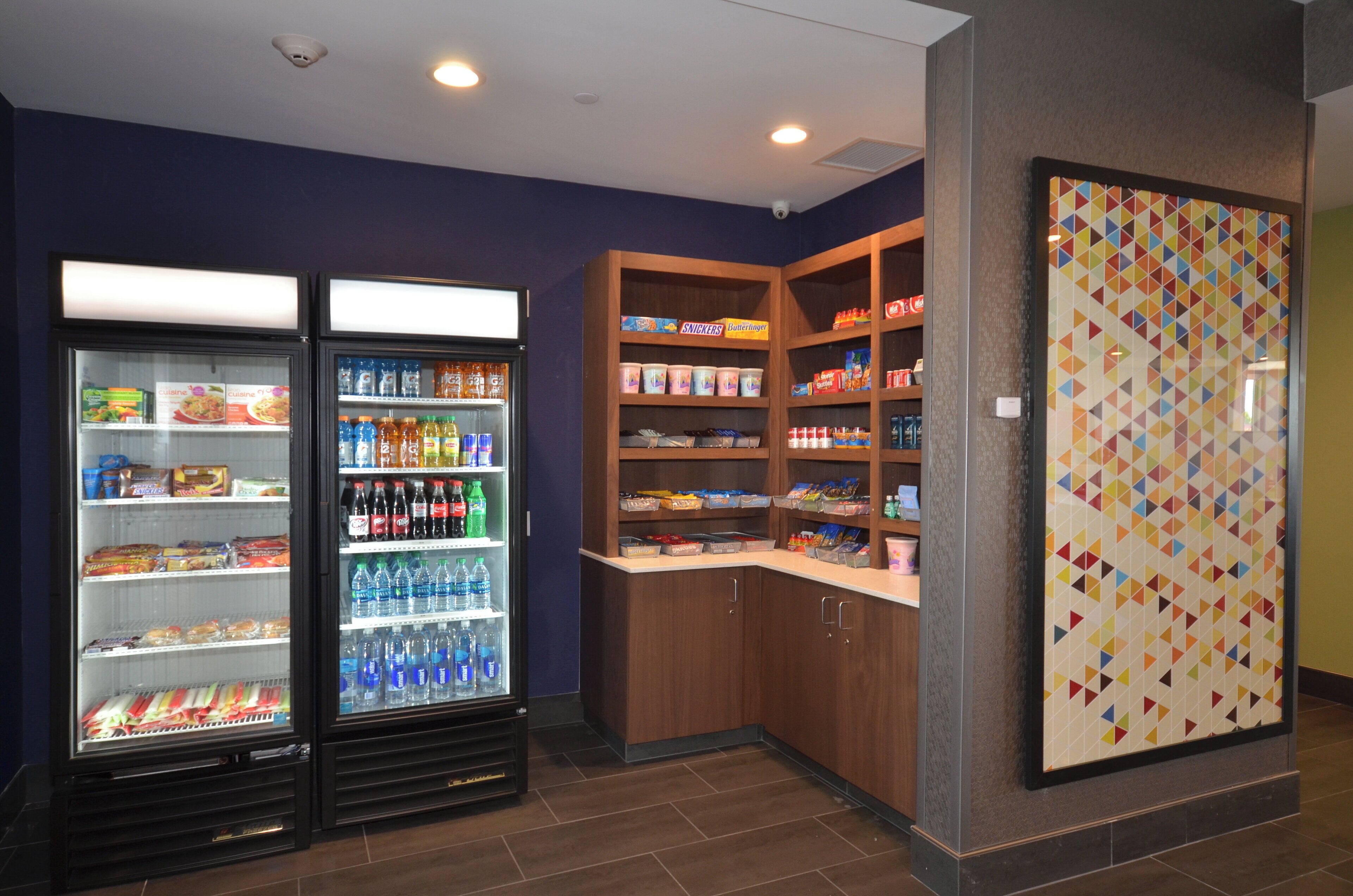 Un área de venta con dispensadores de bebidas refrigeradas y estantes con refrigerios.