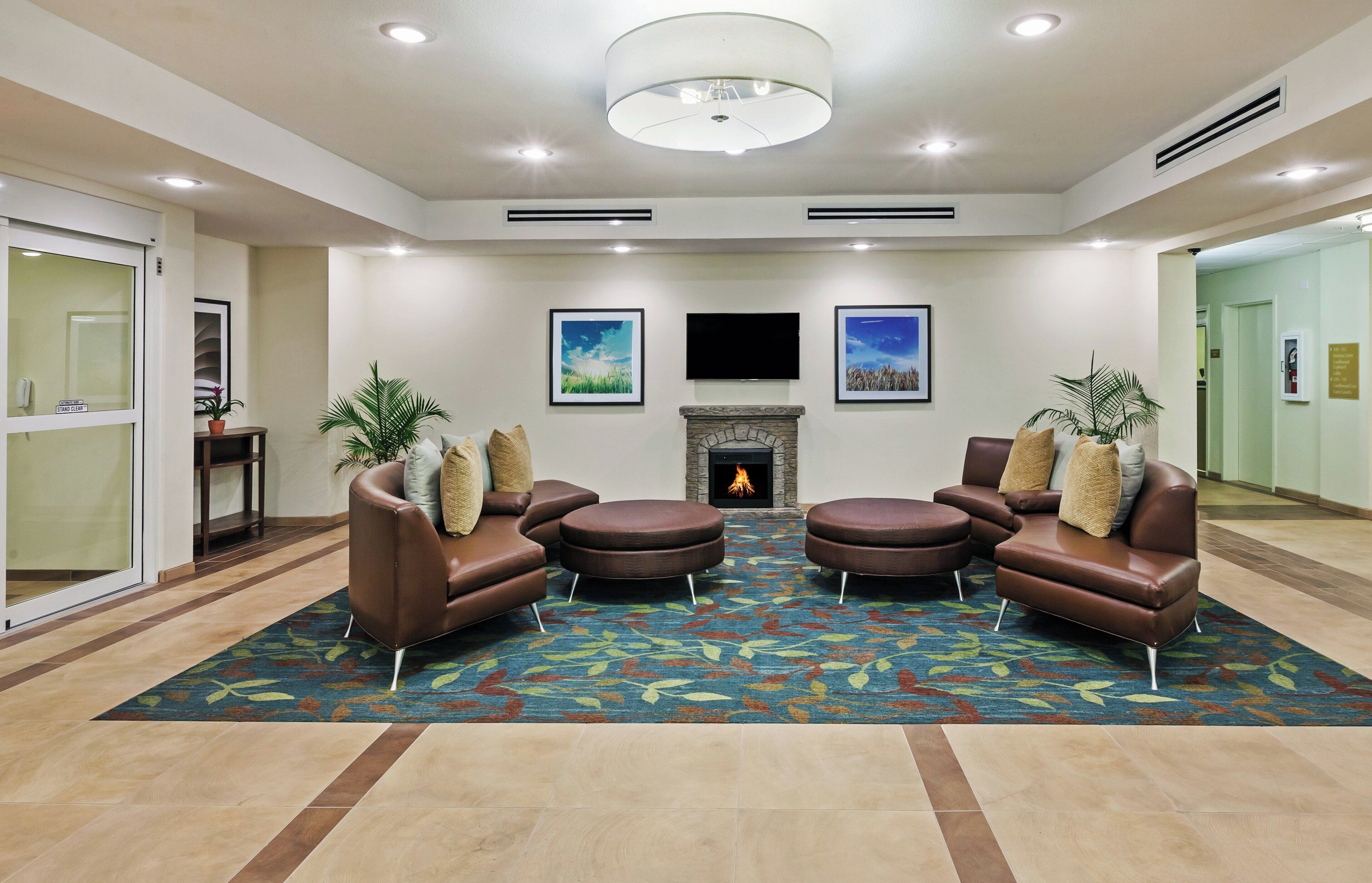 A lobby with a fireplace, leather sofas, and a patterned carpet.