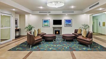A lobby with a fireplace, leather sofas, and a patterned carpet.