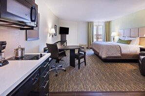 Une chambre d’hôtel équipée d’une kitchenette, d’un lit, d’un bureau et d’une télévision.