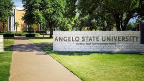 Een bord voor Angelo State University met een pad dat naar de ingang leidt.