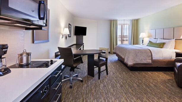 A hotel room with a kitchenette, a bed, a desk, and a television. - Candlewood Suites San Angelo TX by IHG (San Angelo)