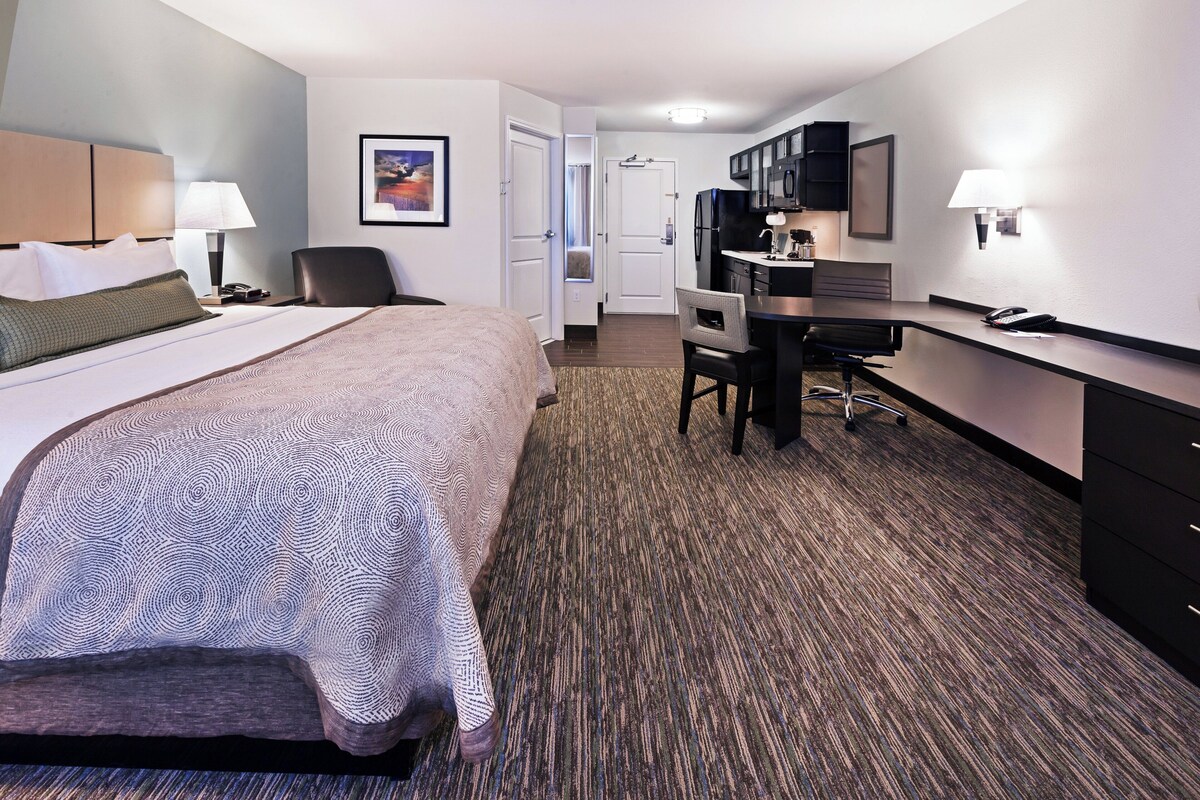 Een hotelkamer met een bed, bureau, stoel en kitchenette.