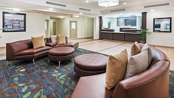 A modern hotel lobby with leather sofas, a patterned rug, and a reception desk.