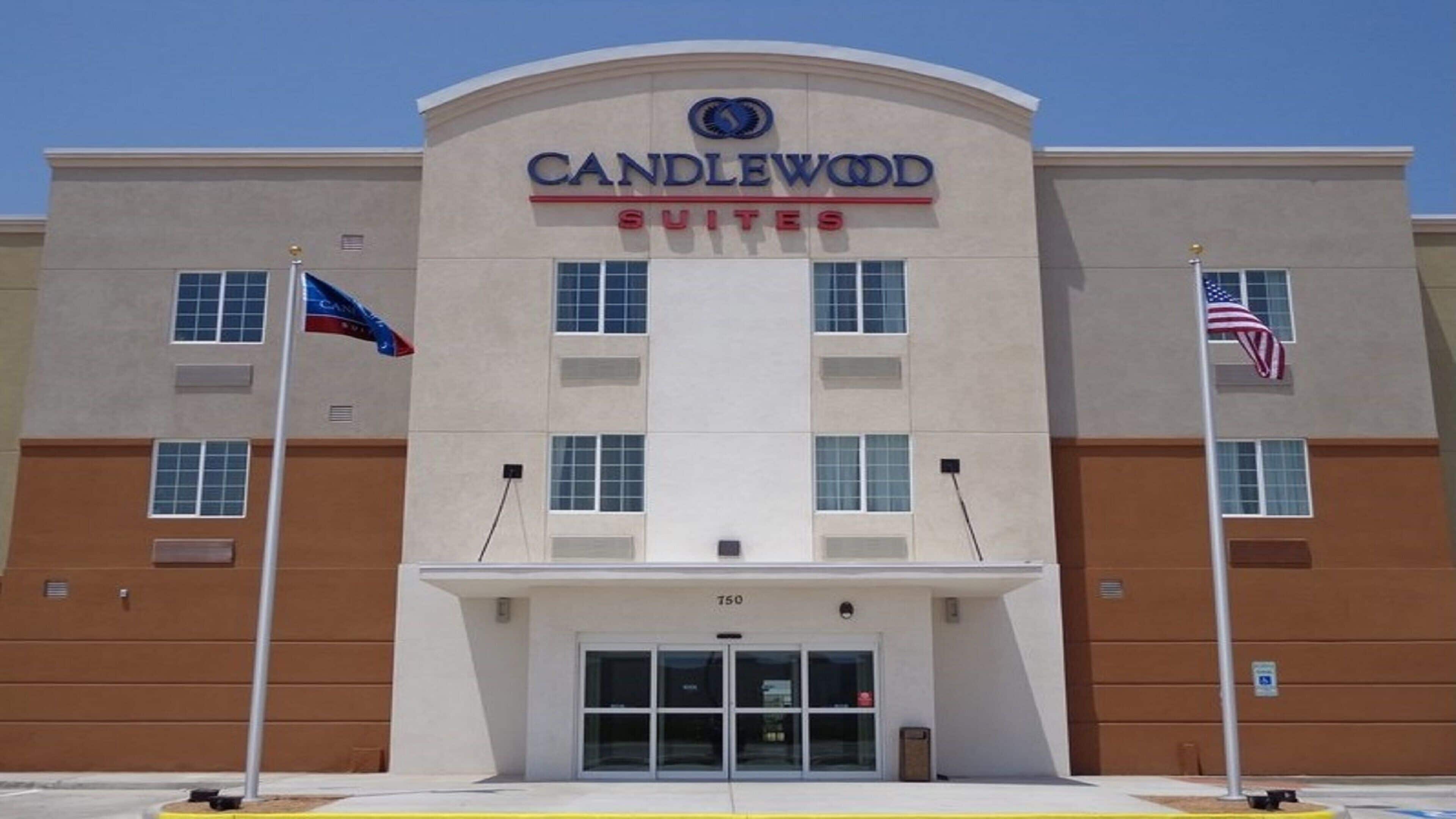 A hotel named Candlewood Suites with a clear entrance and two flags.