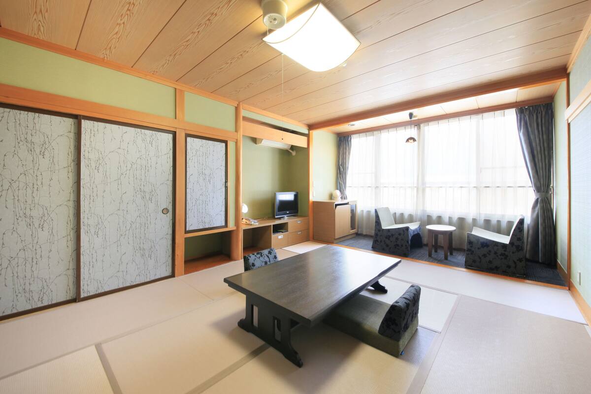 Una habitación japonesa tradicional con suelo de tatami, una mesa baja y asientos.