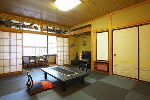 A traditional Japanese room with tatami flooring, a low table, chairs, a television, and sliding doors. - Tabino Yado Marukyo (Nikko)