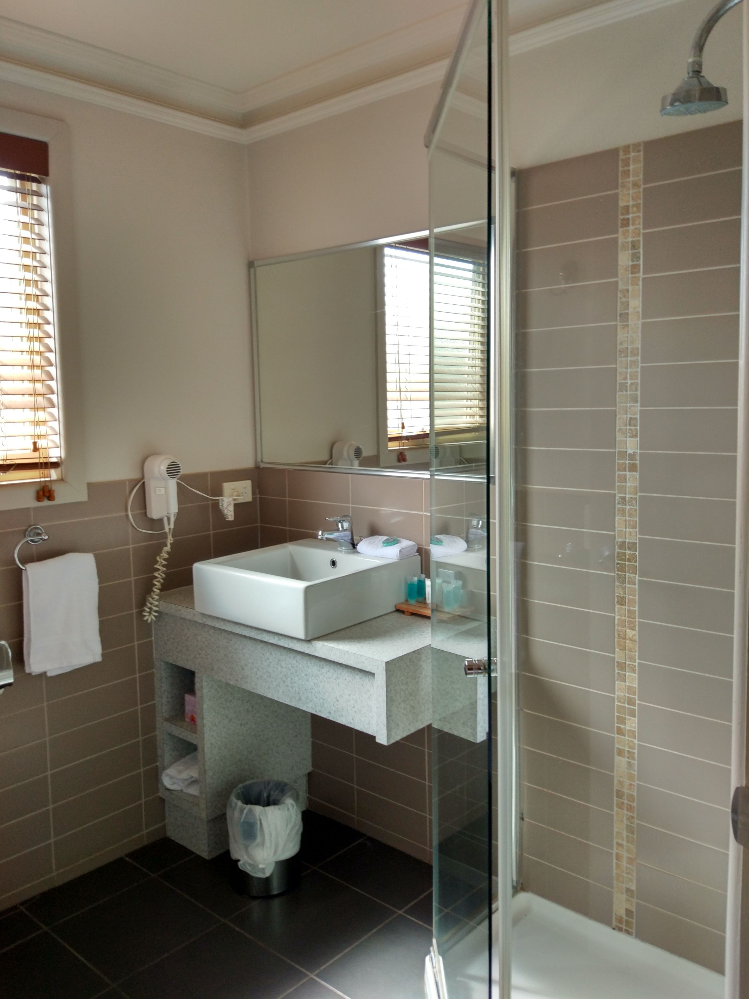 Ein Badezimmer mit Glasdusche, Waschbecken und Spiegel sowie Toilette.