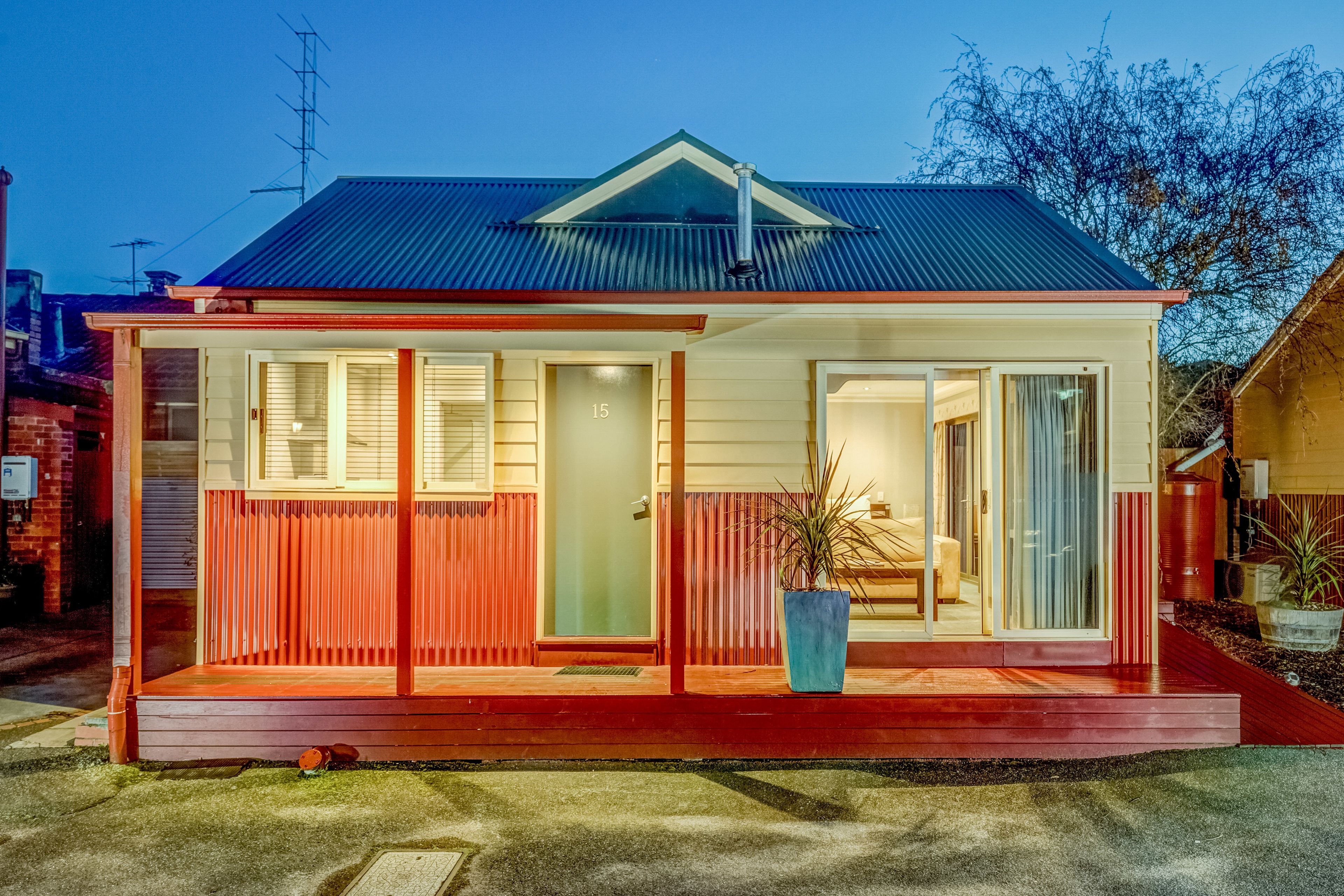 Une maison à deux étages, avec une façade rouge, un balcon et une grande fenêtre.