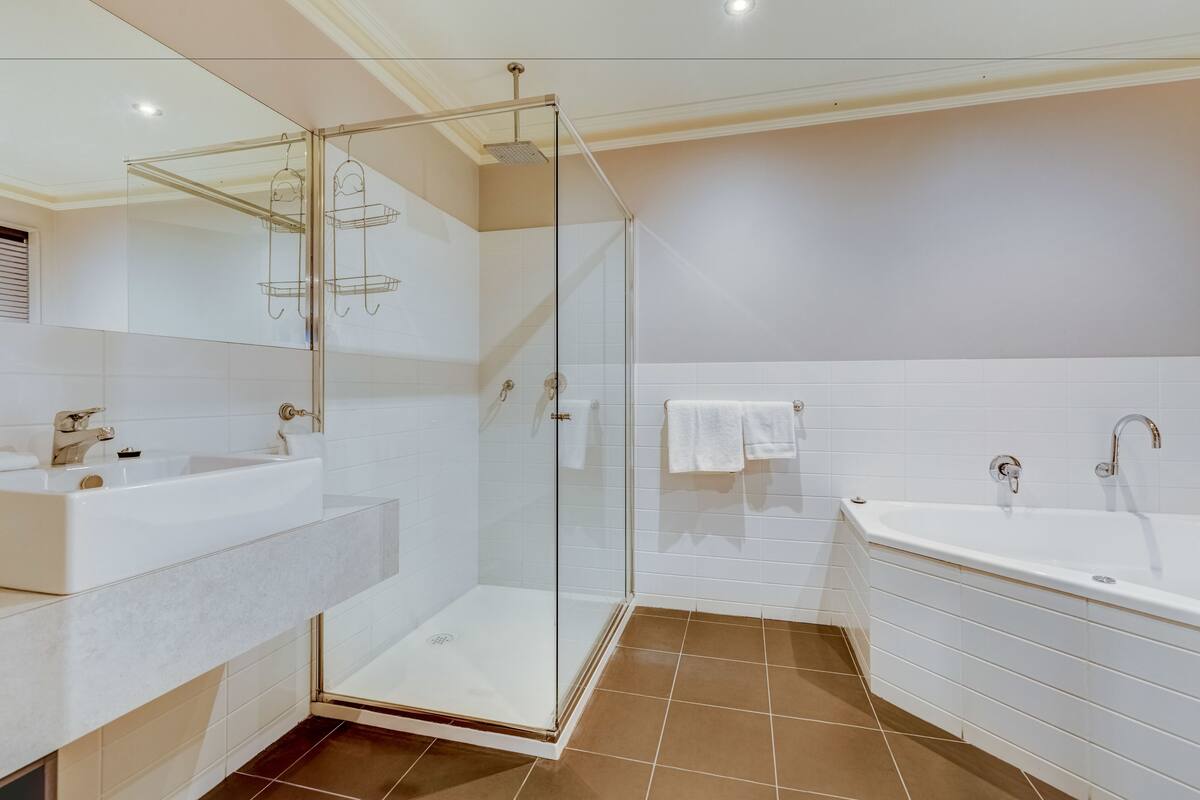 A modern bathroom with a glass-enclosed shower, a large bathtub, and a vanity with a sink.