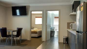 A compact hotel room with a dining area, a bed, and a kitchenette.