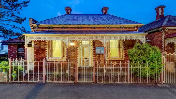 A Victorian-style house with a prominent front porch, a brick facade, and a metal roof. - Seymours on Lydiard (Soldiers Hill)
