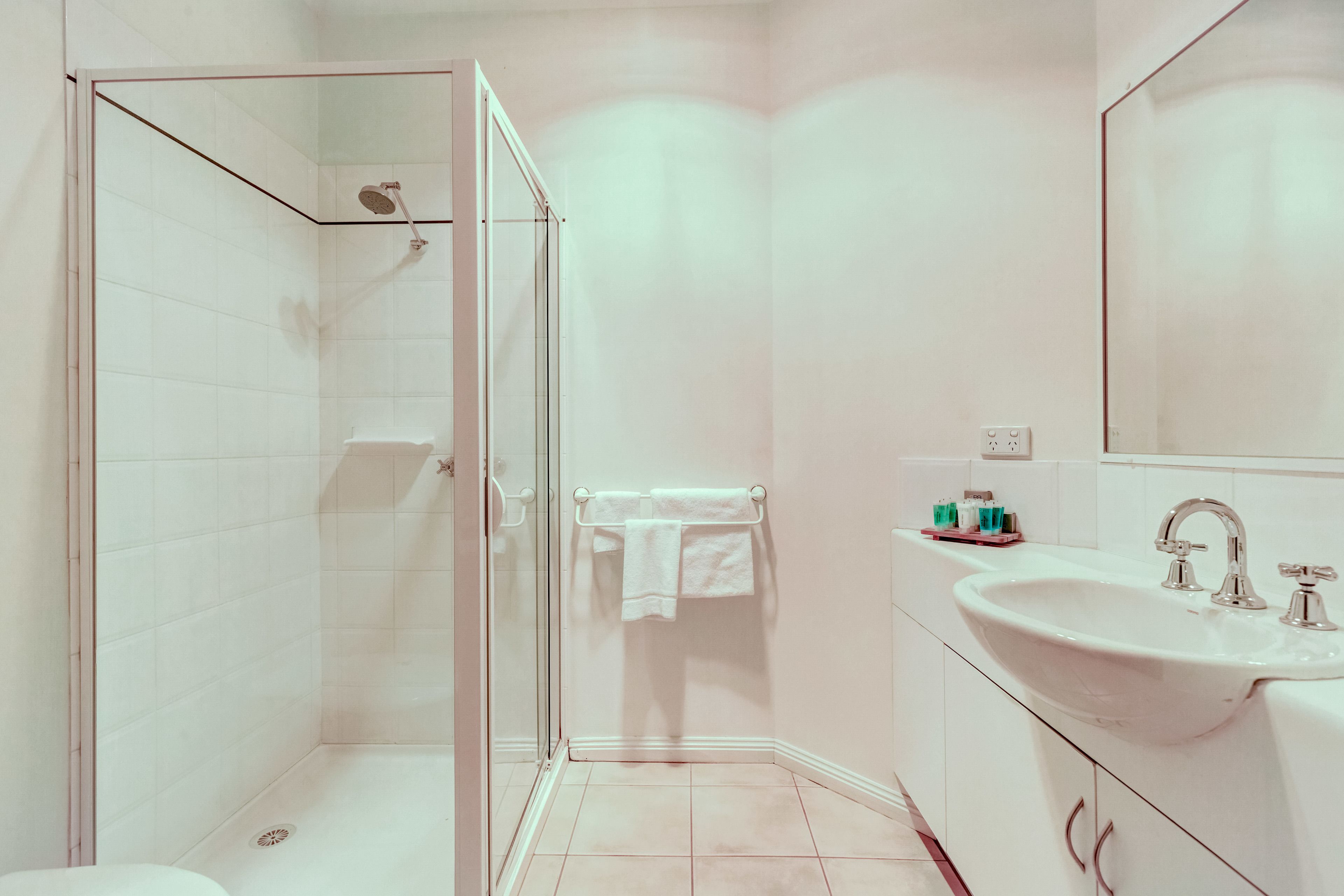 Une salle de bain avec une douche à parois de verre, un lavabo avec un miroir et un porte-serviettes.