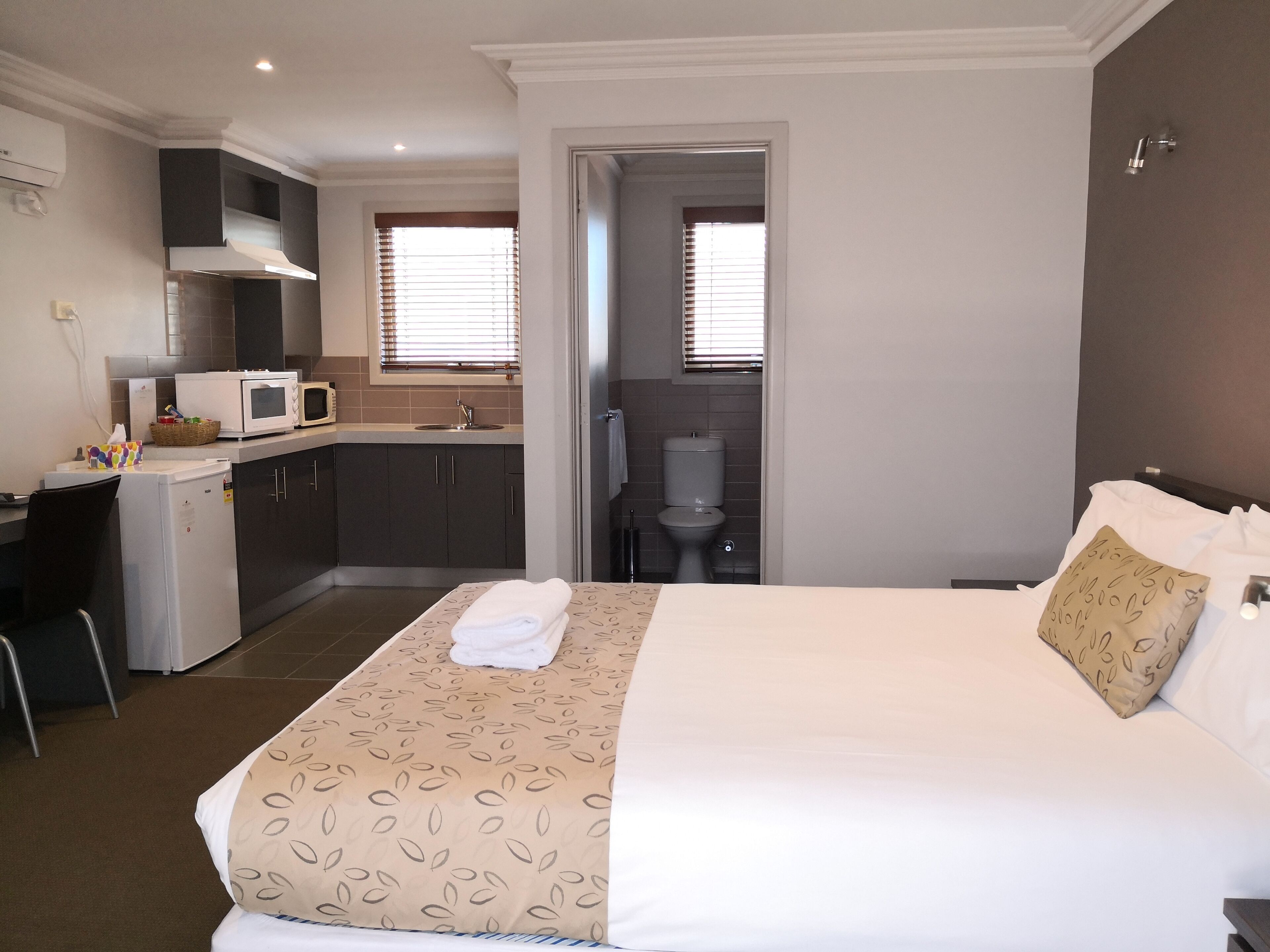 Een hotelkamer met een bed, een bureau, een kitchenette en een badkamer.