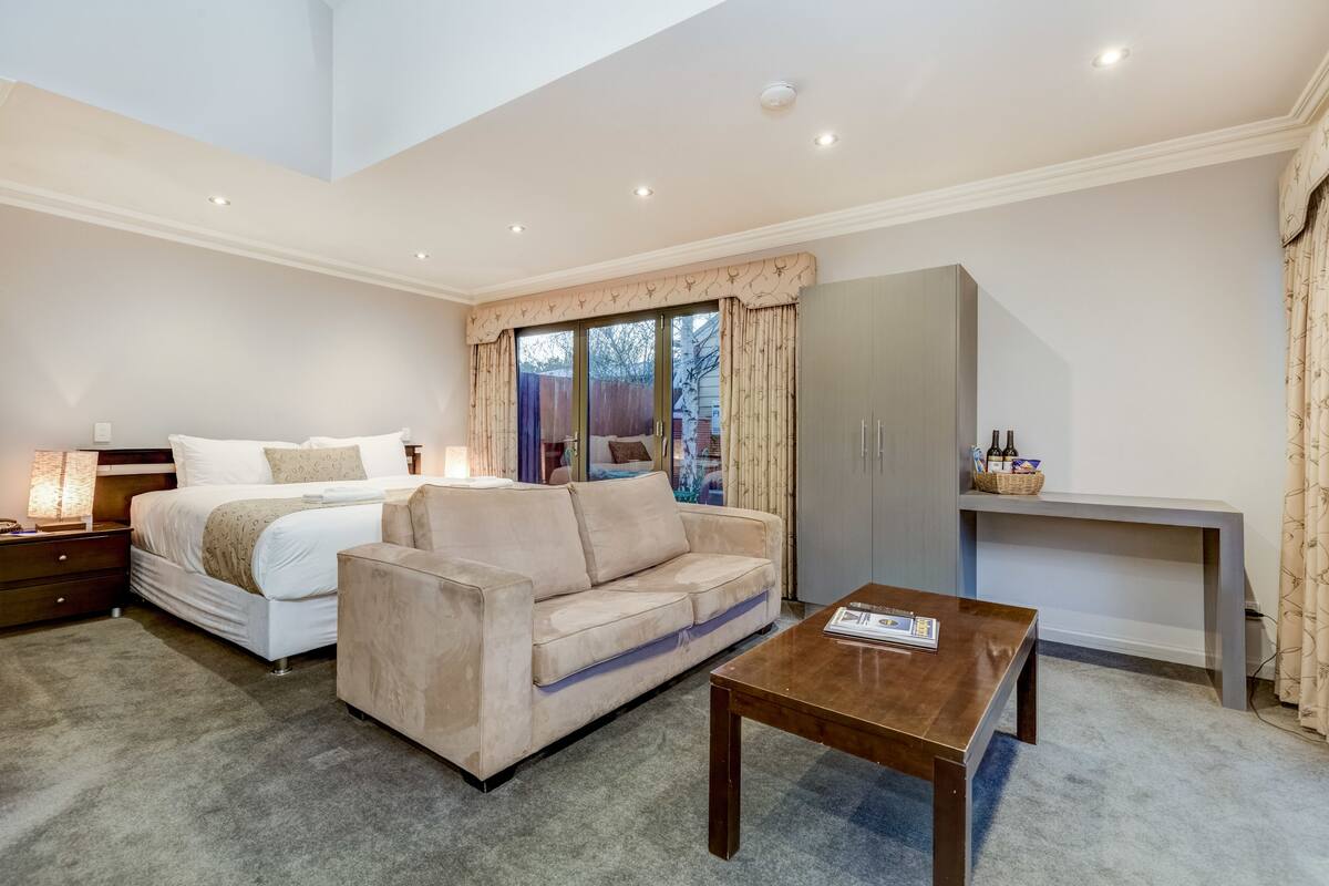 A bedroom with a bed, a sofa, a desk, and a nightstand.