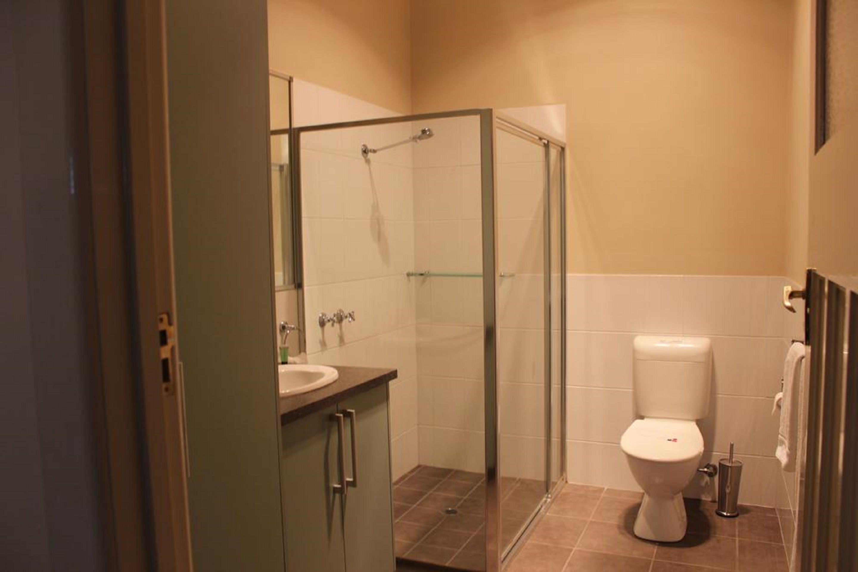 A bathroom with a glass shower enclosure, a toilet, and a sink with a mirror.