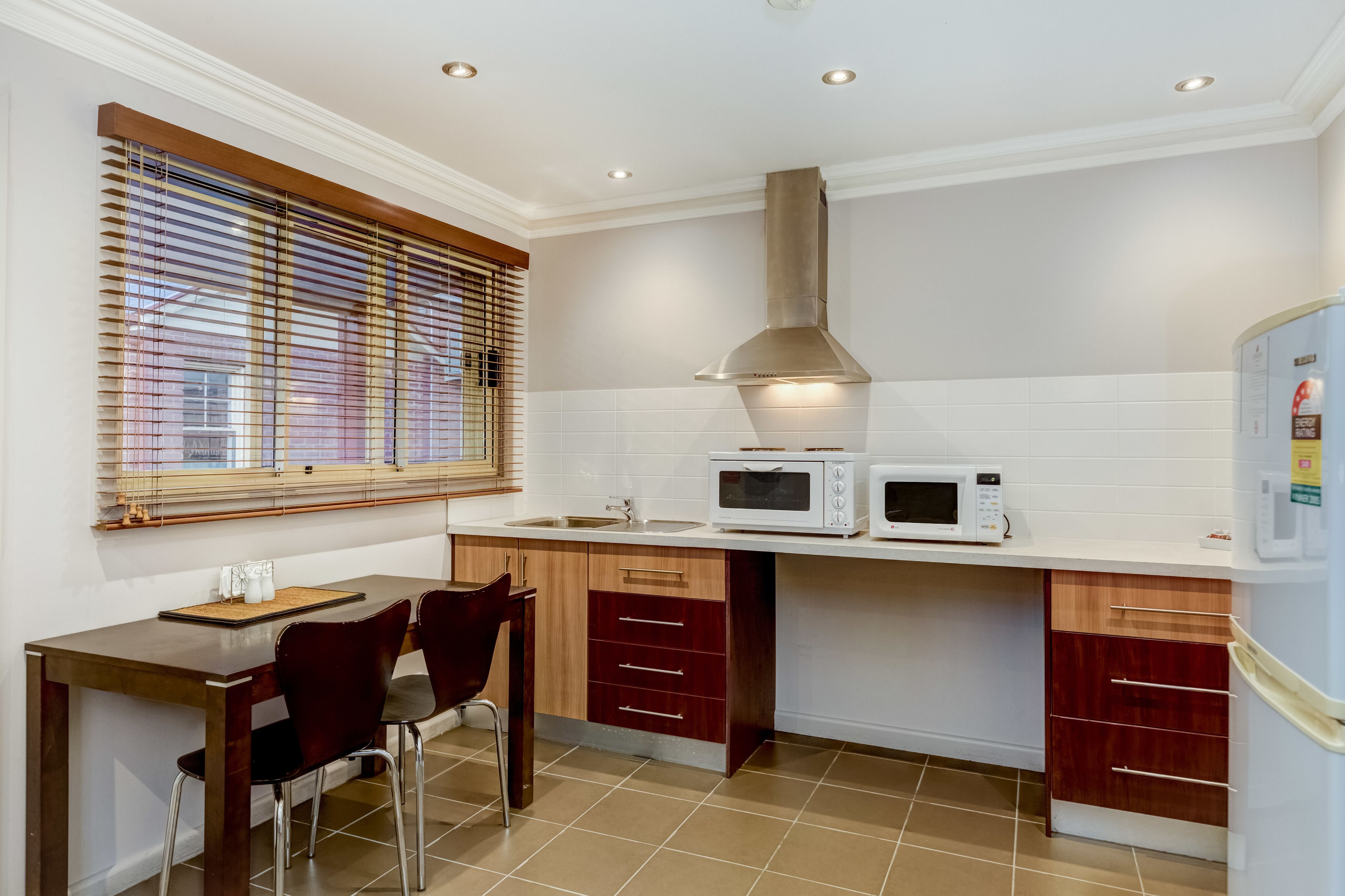 Una cocina compacta con comedor, que incluye microondas, pileta y muebles de madera.