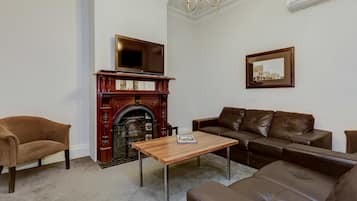 A living room with a fireplace, a sofa, a coffee table, and a television.