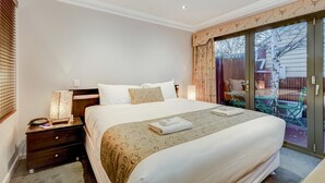 A bedroom with a large bed, a nightstand, a lamp, and a sliding glass door leading to an outdoor area. - Seymours on Lydiard (Soldiers Hill)